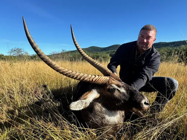 Hunter with a mature waterbuck trophy in South African grassland