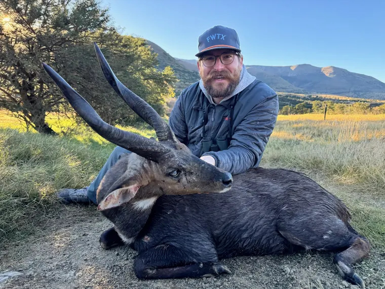 Hunter with a dark coated plains game trophy in scenic Eastern Cape country