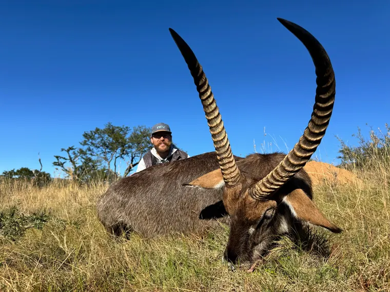 Hunter with a mature antelope trophy beneath a clear blue sky