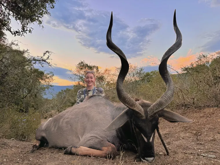 Hunter behind a mature spiral horned trophy at dusk