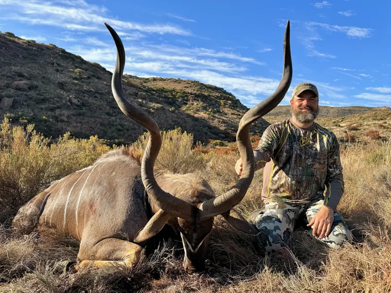 Hunter with a mature spiral horned trophy framed by Eastern Cape mountains