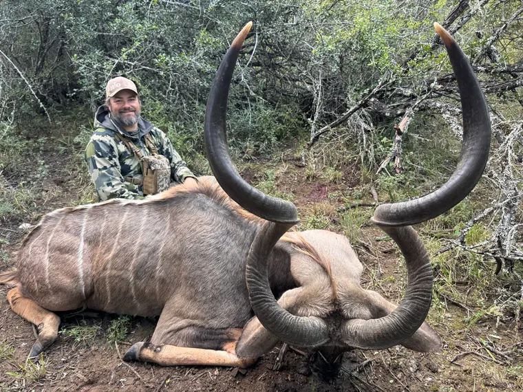 Hunter with a mature spiral horned trophy in Eastern Cape woodland