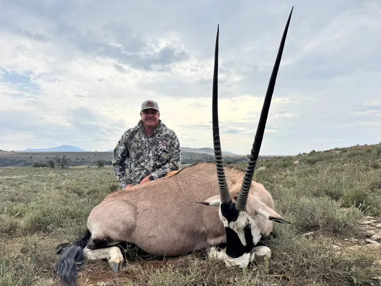 Hunter with a gemsbok trophy in open Eastern Cape terrain