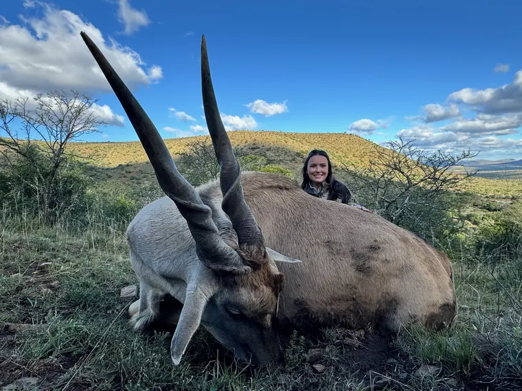 Hunter with a long horned gemsbok trophy in mountain country