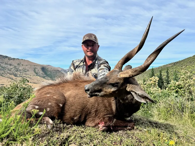 Hunter wearing a Heart of Texas Outfitters cap with a spiral horned trophy in South Africa