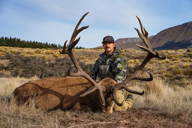 Hunter with a mature red stag trophy in New Zealand high country