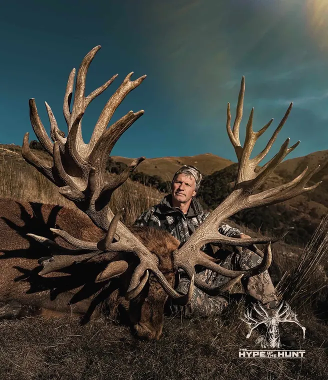 Hunter behind an exceptionally wide red stag trophy in New Zealand