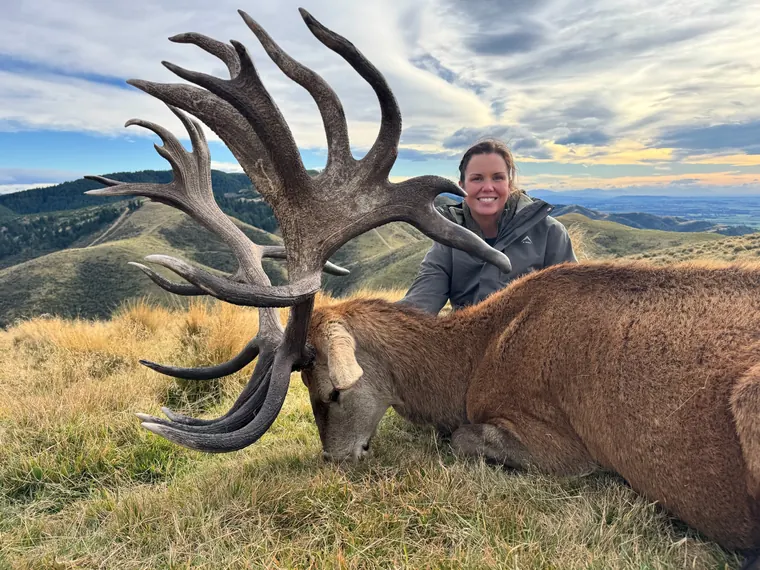 Hunter with a mature red stag overlooking New Zealand mountain valleys