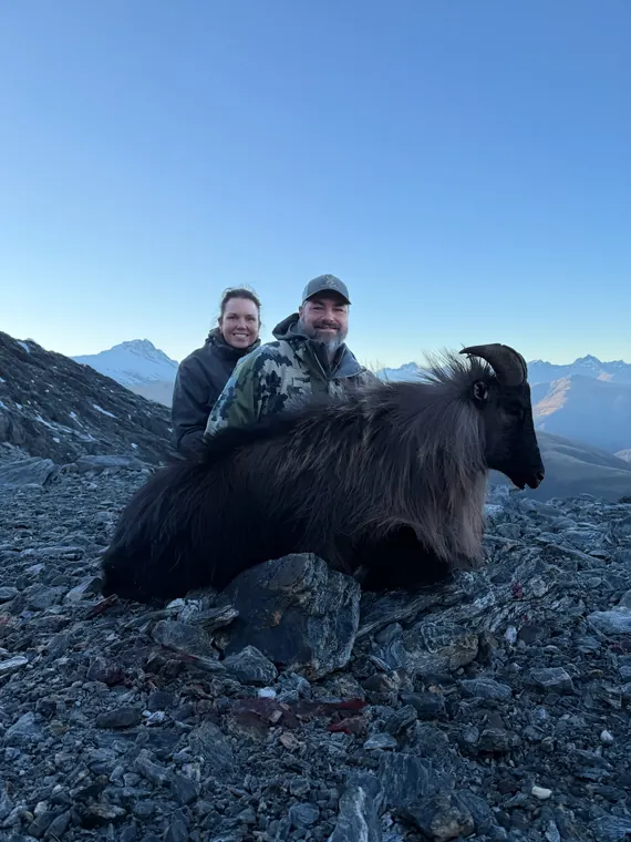 Two hunters with a Himalayan tahr trophy in rocky alpine terrain