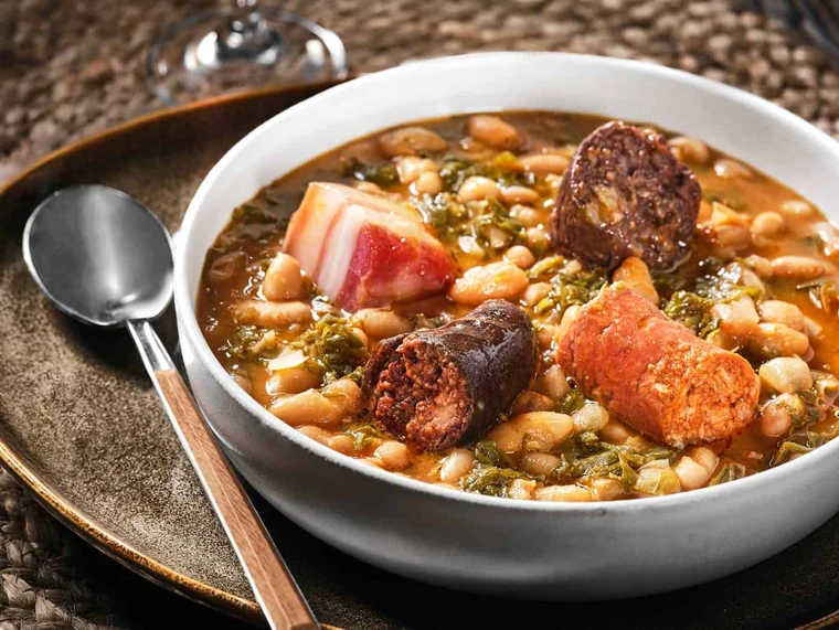 Bowl of cocido montañés with beans, sausage, and vegetables