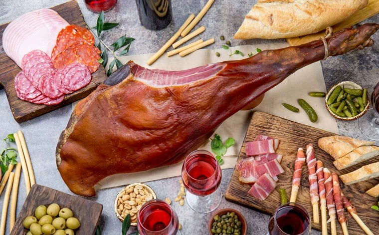 Cured ham with sliced meats, bread, and olives
