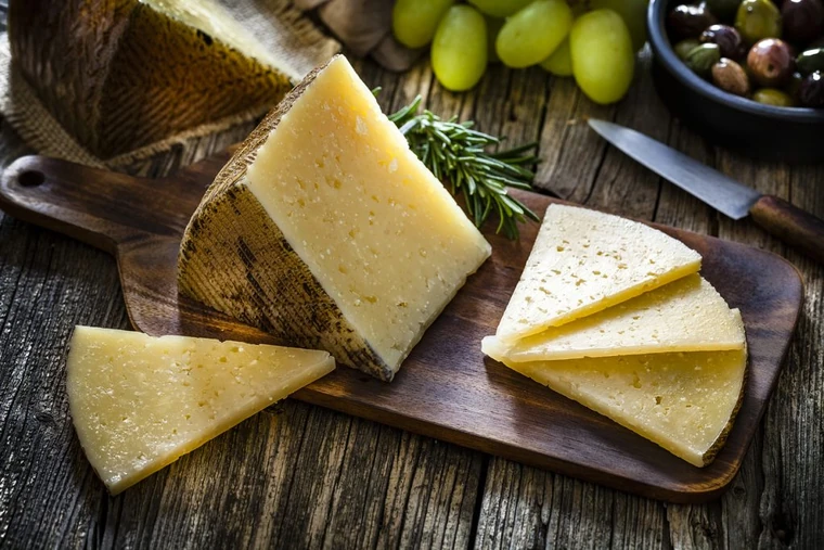 Manchego cheese wedges with olives on a wooden table