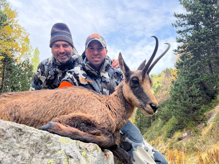 Two hunters with a Pyrenean chamois in mountain country, Spain