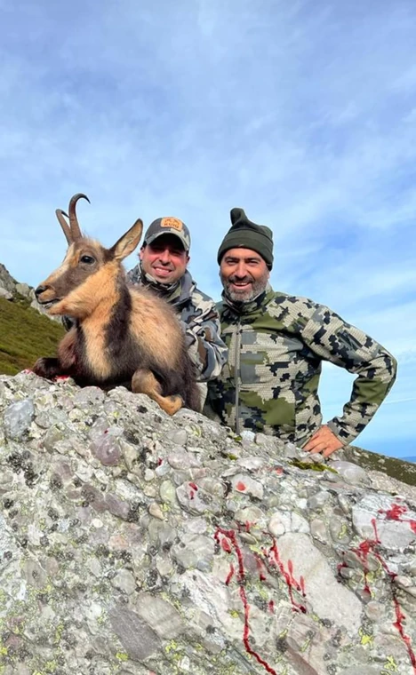 Two hunters with a Pyrenean chamois on a rocky ridge, Spain