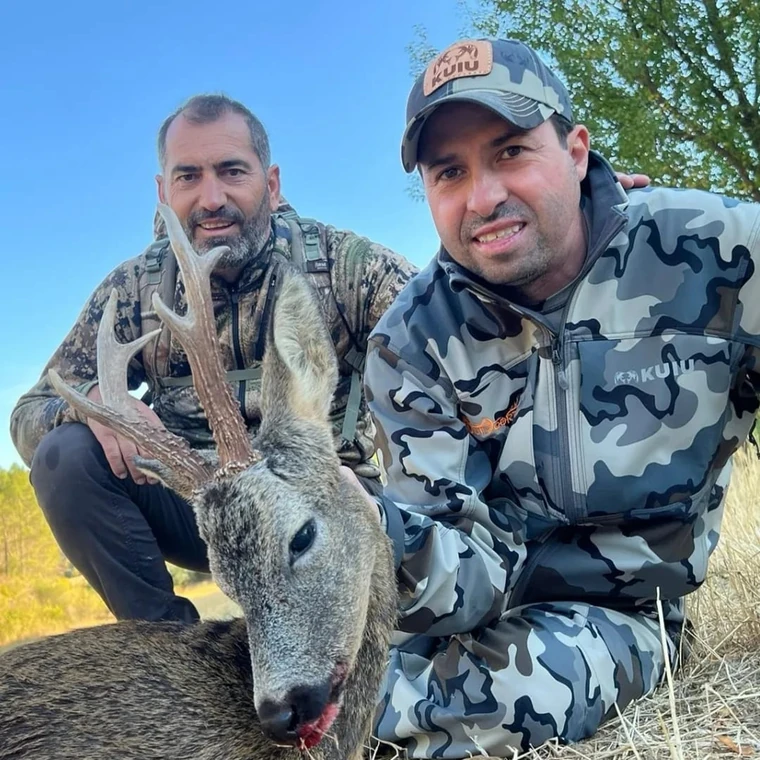 Two hunters with a roe deer beneath a blue sky, Spain