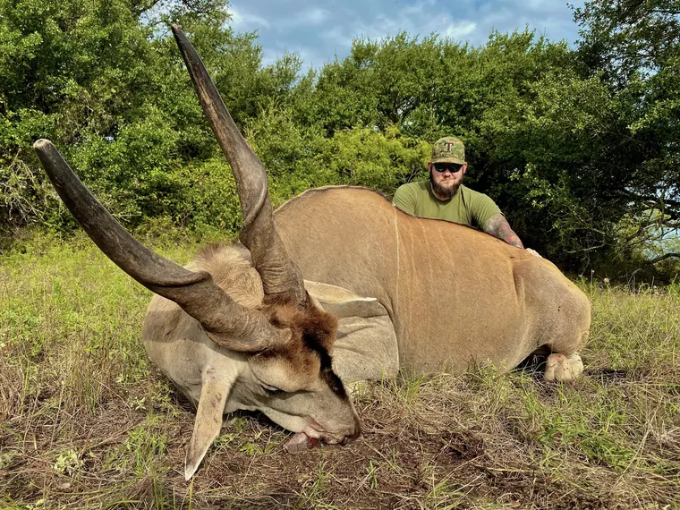 Hunter with an eland in green Dublin ranch country