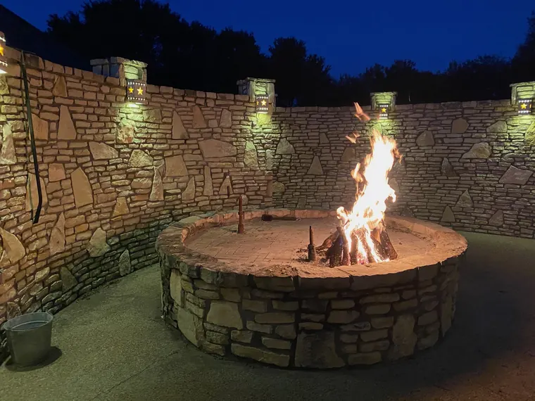 Round stone firepit glowing in the Dublin lodge courtyard at night