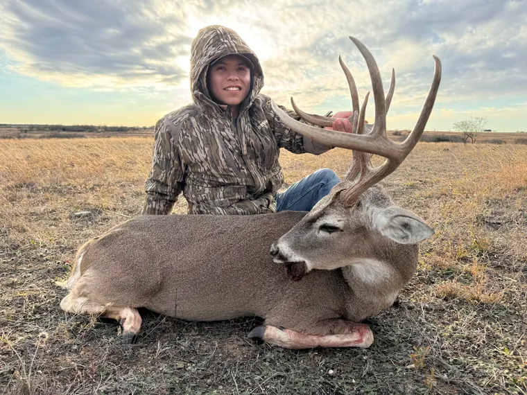Hunter with a whitetail buck in open Dublin ranch country