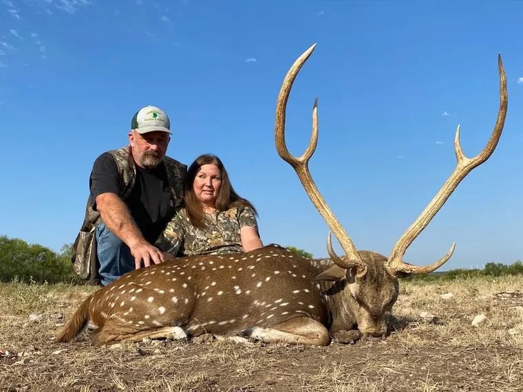 Two hunters with an axis buck in Texas ranch country