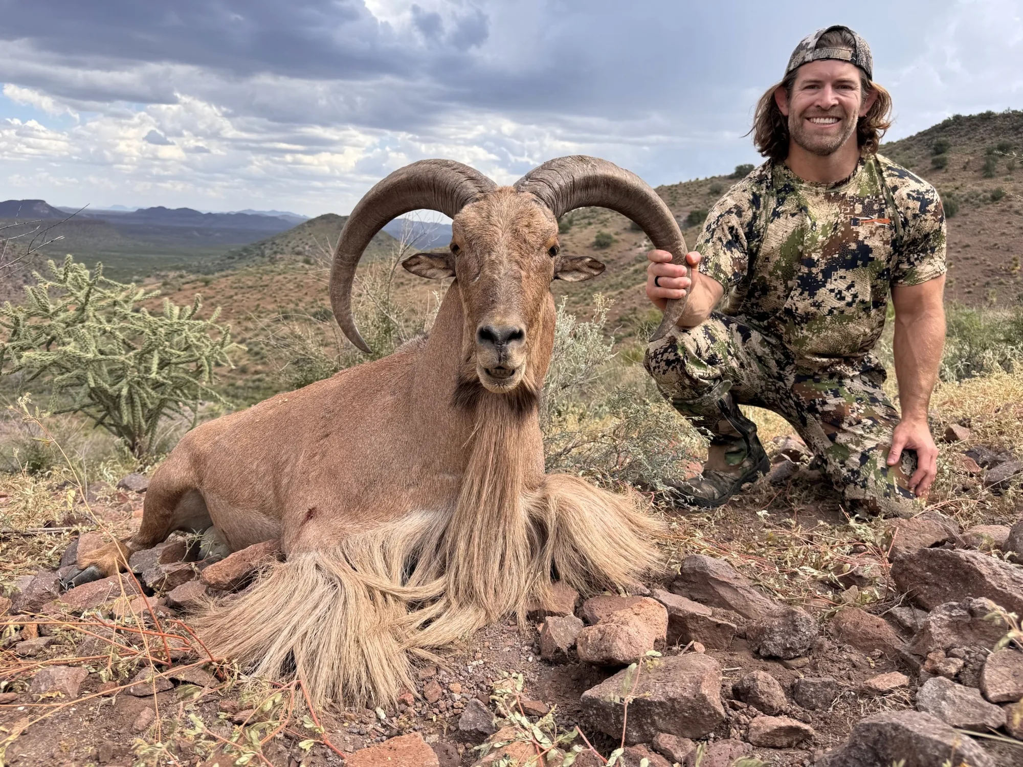 Hunter with an aoudad ram in rocky West Texas mountain country